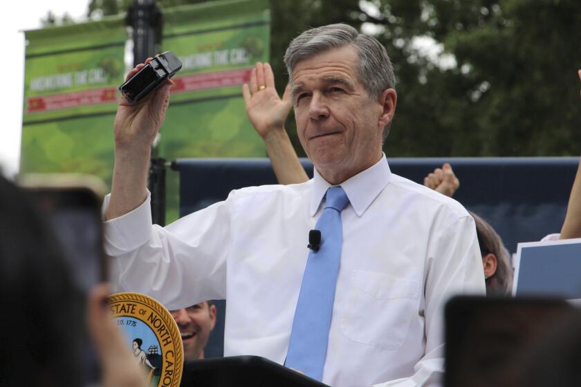 North Carolina Democratic Gov. Roy Cooper affixes his veto stamp to a bill banning nearly all abortions after 12 weeks of pregnancy at a public rally Saturday, May 13, 2023, in Raleigh, N.C. The veto launches a major test for leaders of the GOP-controlled General Assembly to attempt to override Cooper’s veto after they recently gained veto-proof majorities in both chambers. (AP Photo/Hannah Schoenbaum)