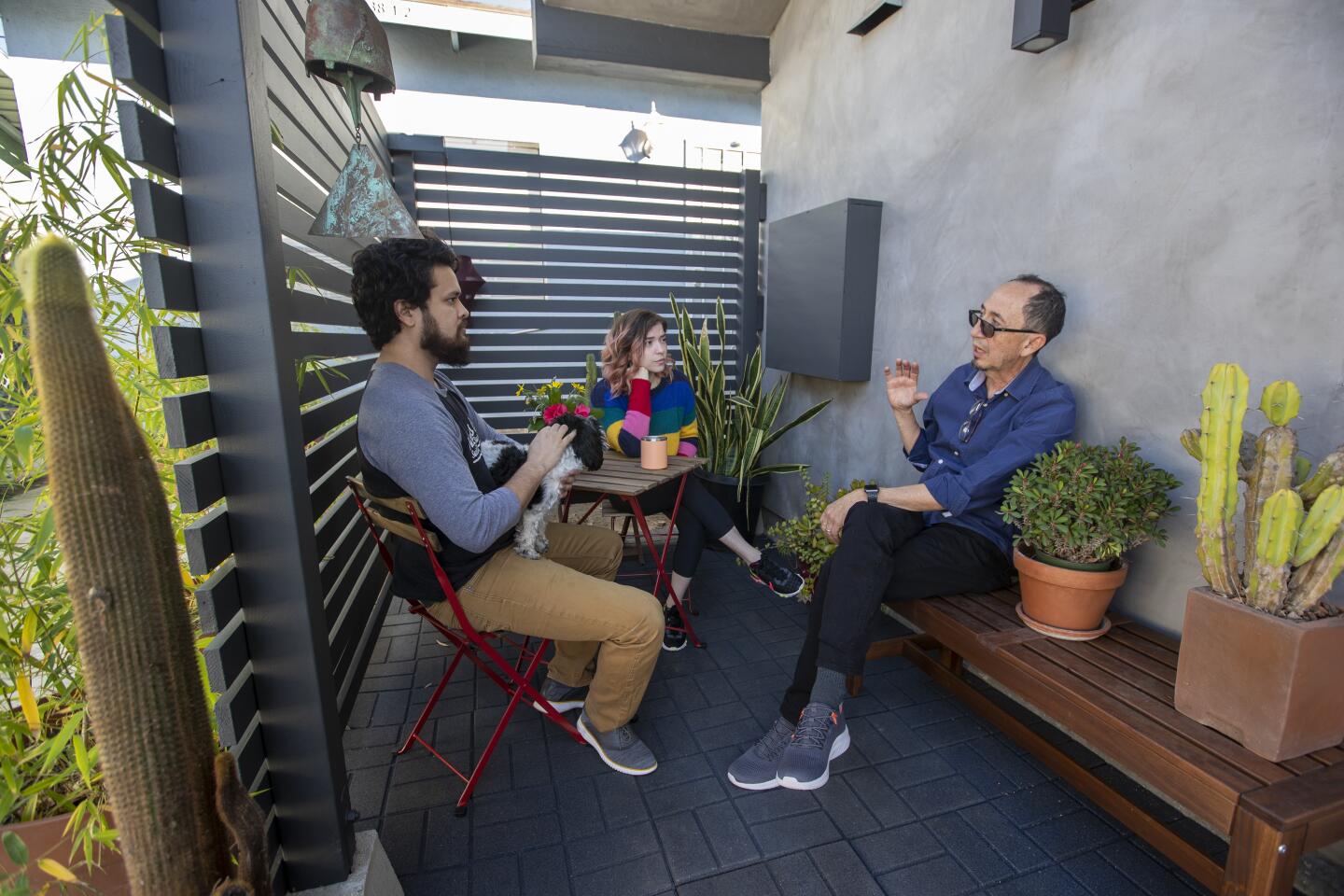 Two men and a woman sit in a small patio.