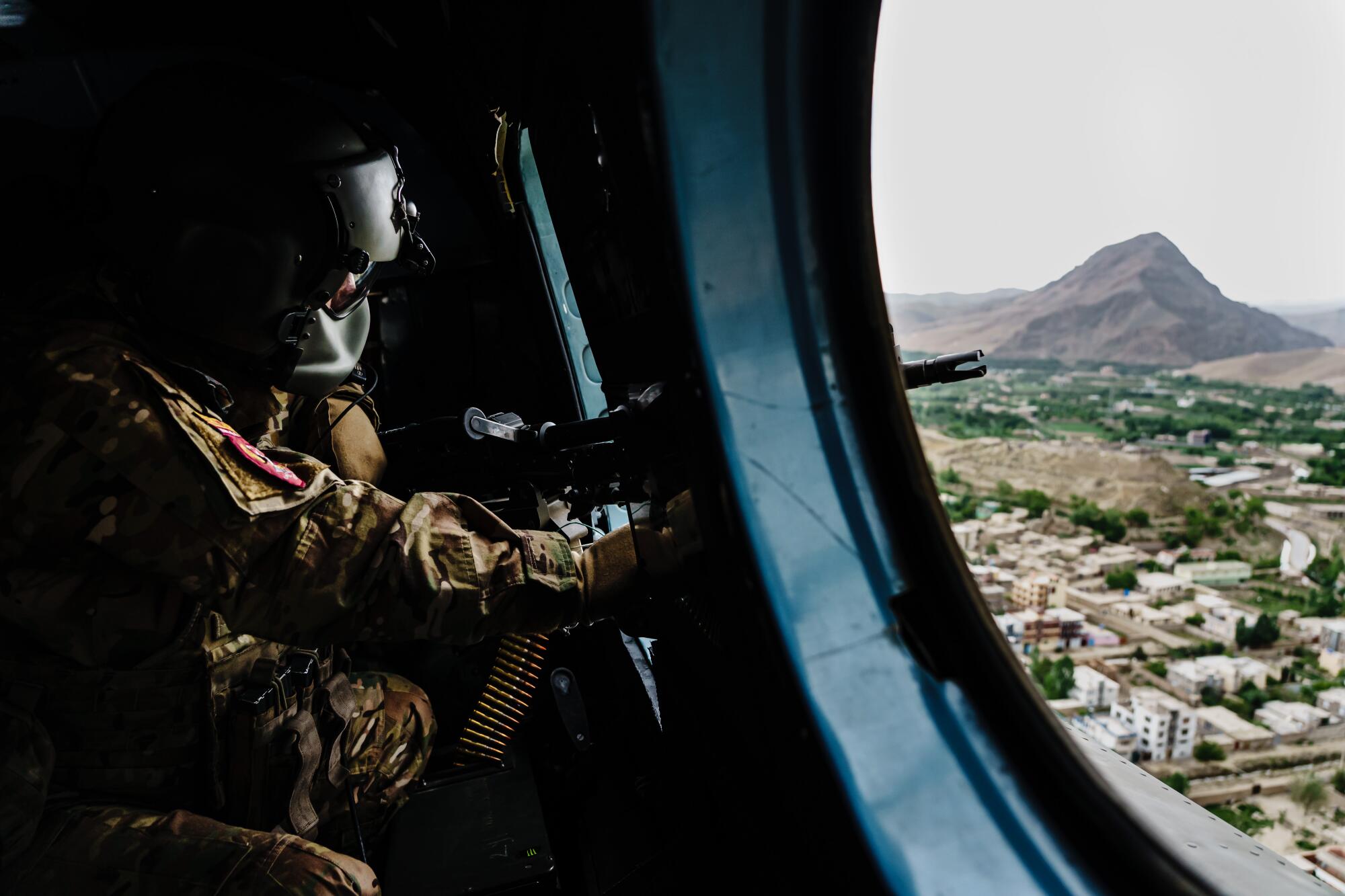 A soldier looks out of a helicopter.