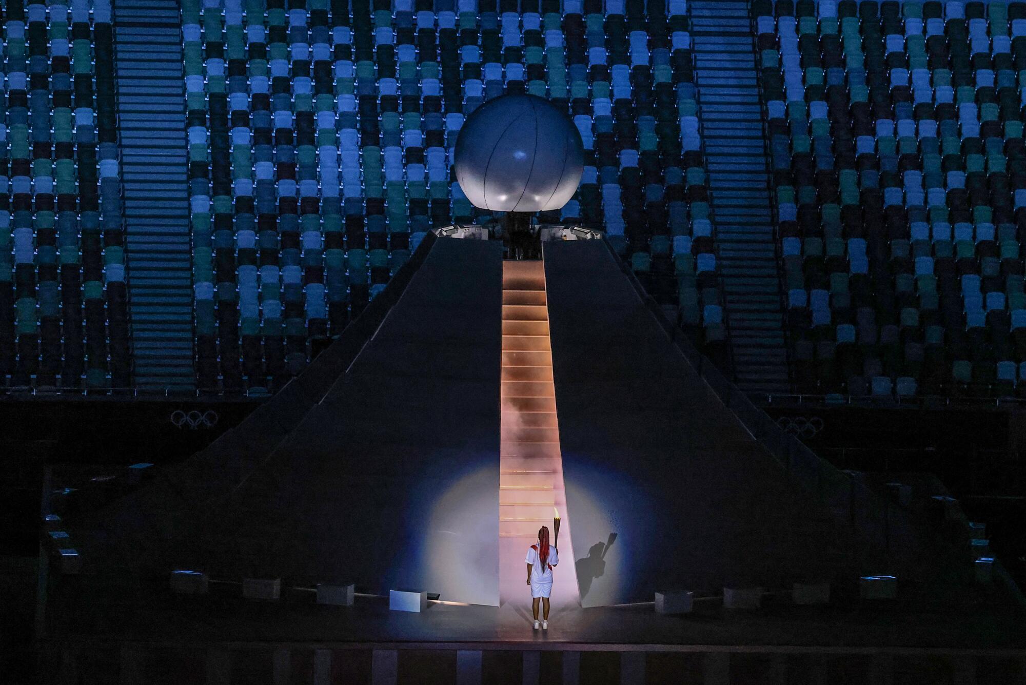 Naomi Osaka prepares to scale stairs to light the Olympic flame at the Tokyo Olympics opening ceremony.