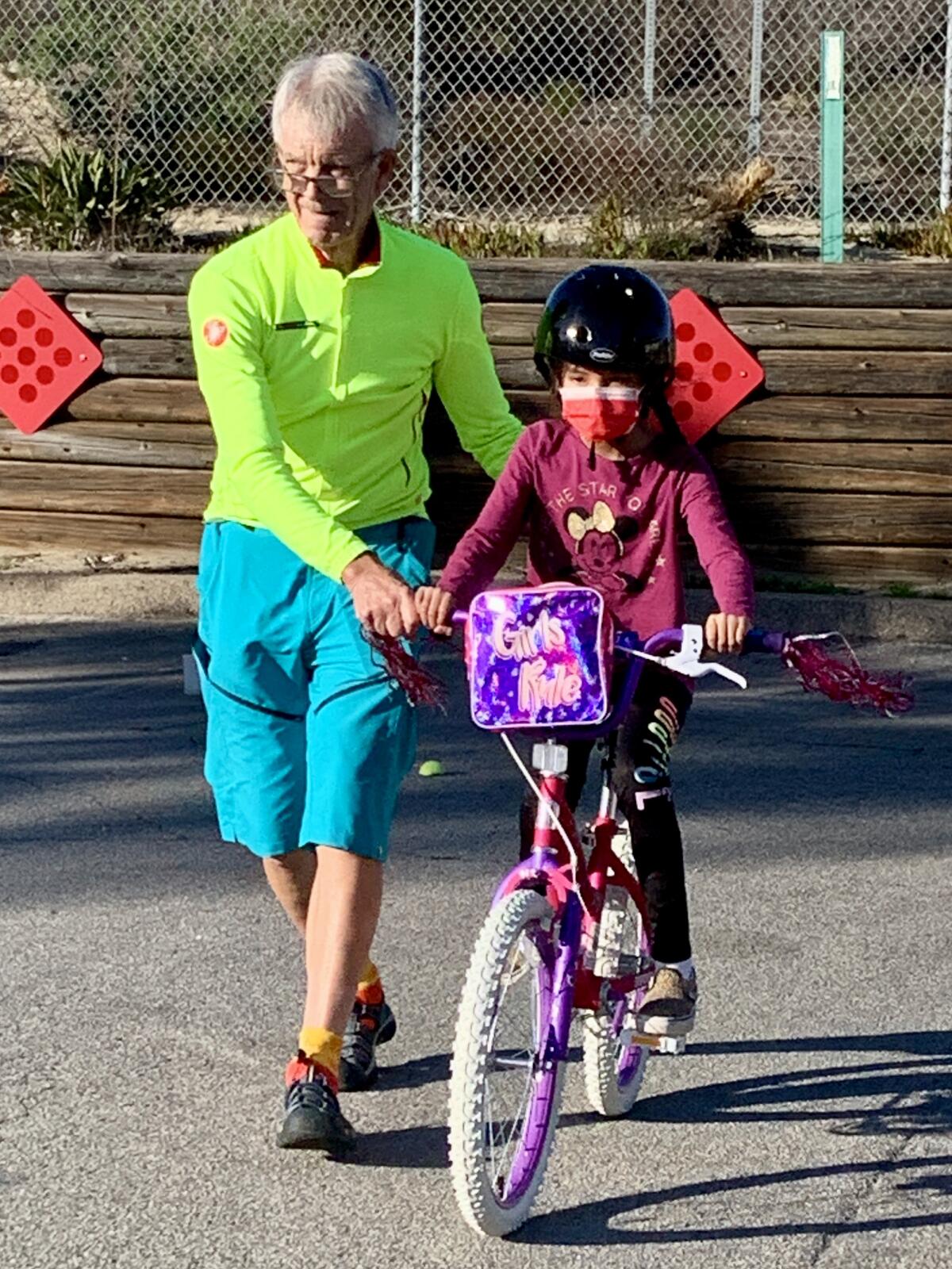 Karl Rudnick helps a student practice riding her new bike.