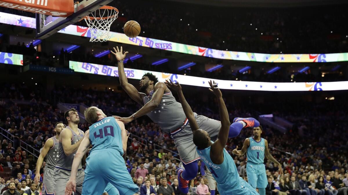 Philadelphia 76ers' Joel Embiid, center, tries to get a shot past Charlotte Hornets' Michael Kidd-Gilchrist, right, and Cody Zeller during the second half.