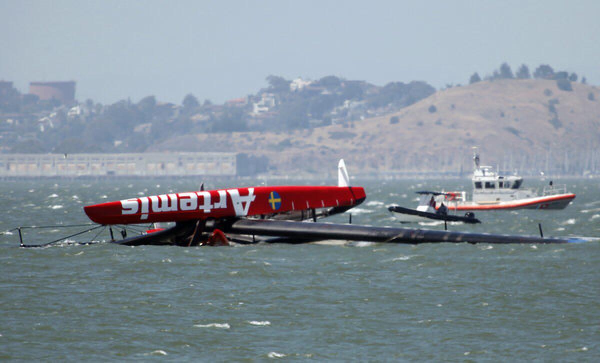 The overturned Artemis Racing AC72 catamaran, an America's Cup entry from Sweden, is towed past Treasure Island after the boat capsized during training in San Francisco Bay .