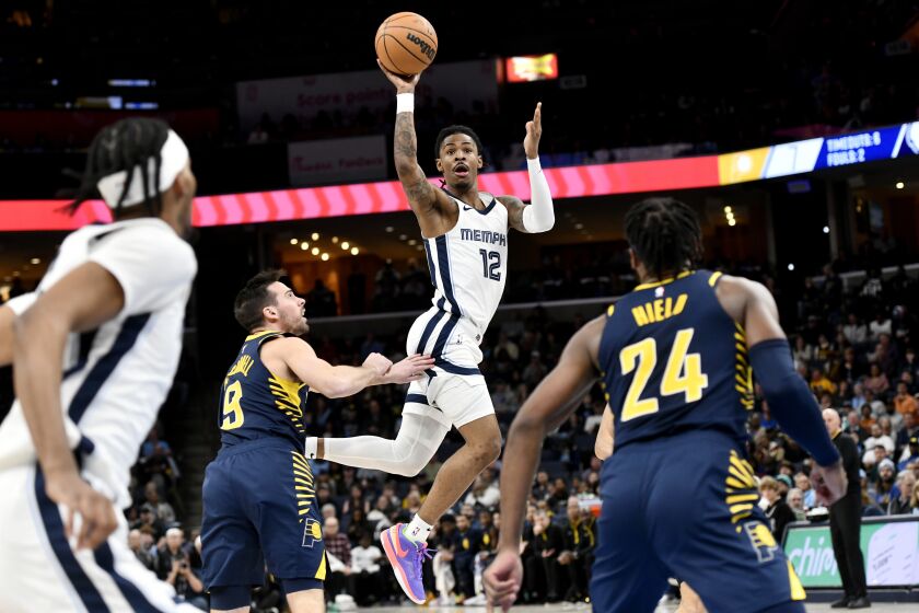 Memphis Grizzlies guard Ja Morant (12) passes the ball over Indiana Pacers guard T.J. McConnell (9) in the first half of an NBA basketball game Sunday, Jan. 29, 2023, in Memphis, Tenn. (AP Photo/Brandon Dill)