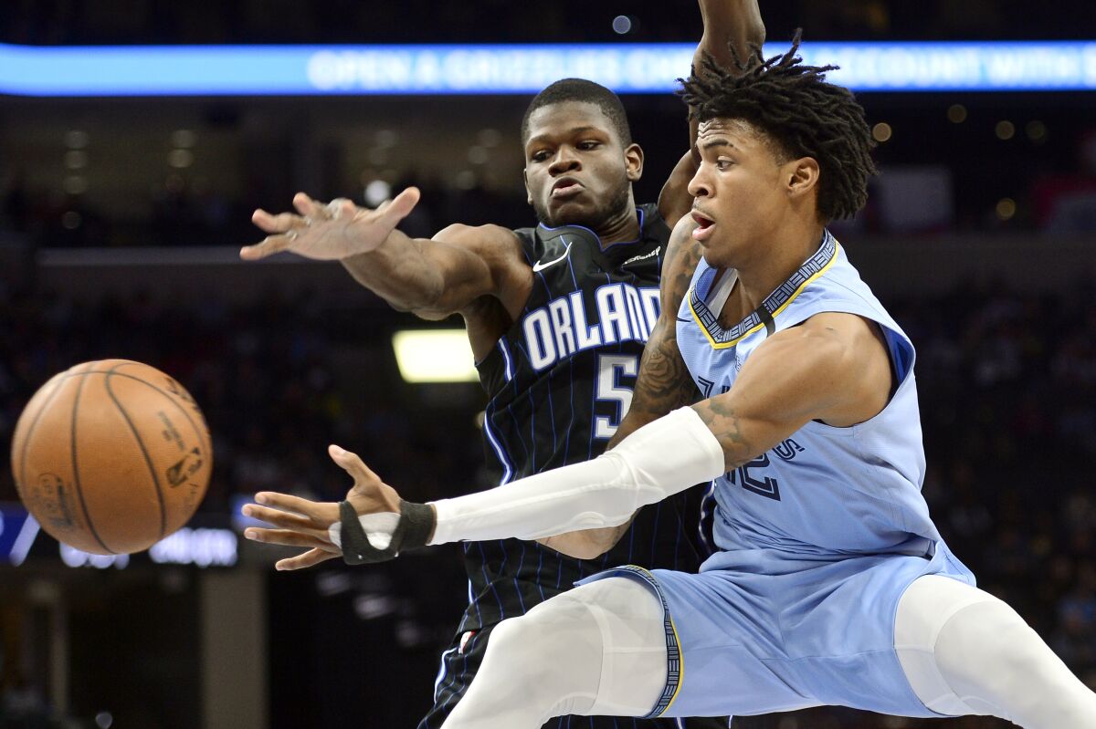 FILE - In this March 10, 2020, file photo, Memphis Grizzlies guard Ja Morant, right, passes the ball as Orlando Magic center Mo Bamba (5) defends during the first half of an NBA basketball game in Memphis, Tenn. Morant has taken advantage of the NBA's hiatus, adding 12 pounds of muscle to help absorb contact when the NBA's likely rookie of the year fearlessly attacks the basketball. (AP Photo/Brandon Dill, File)