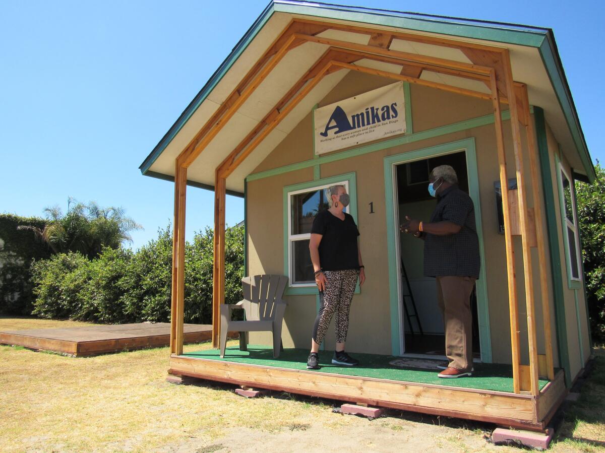 Two people stand outside a demonstration cabin in El Cajon.