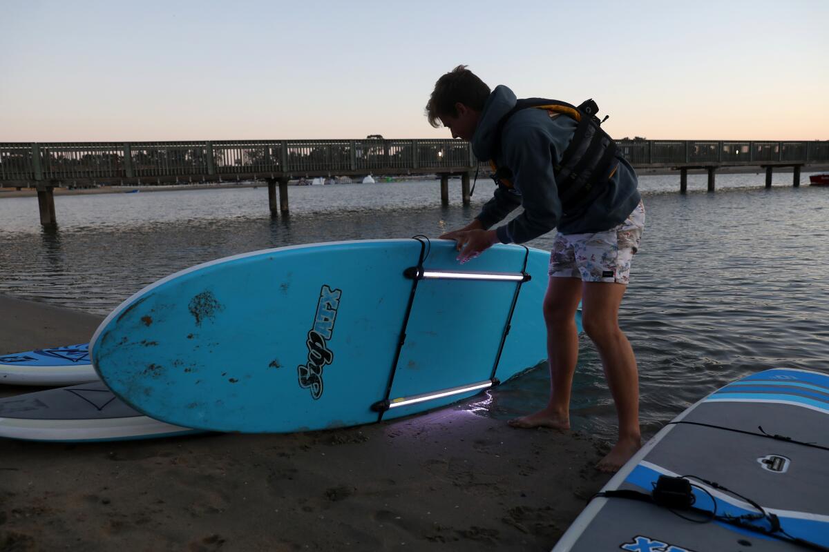 A young man inspects a paddle board.