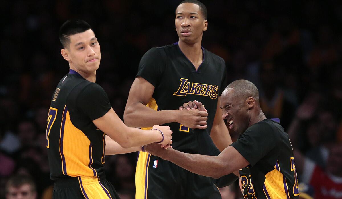 Lakers guard Kobe Bryant is helped to his feet by teammates Jeremy Lin, left, and Wesley Johnson after getting hit in the head and drawing a foul against Clippers guard Jamal Crawford.