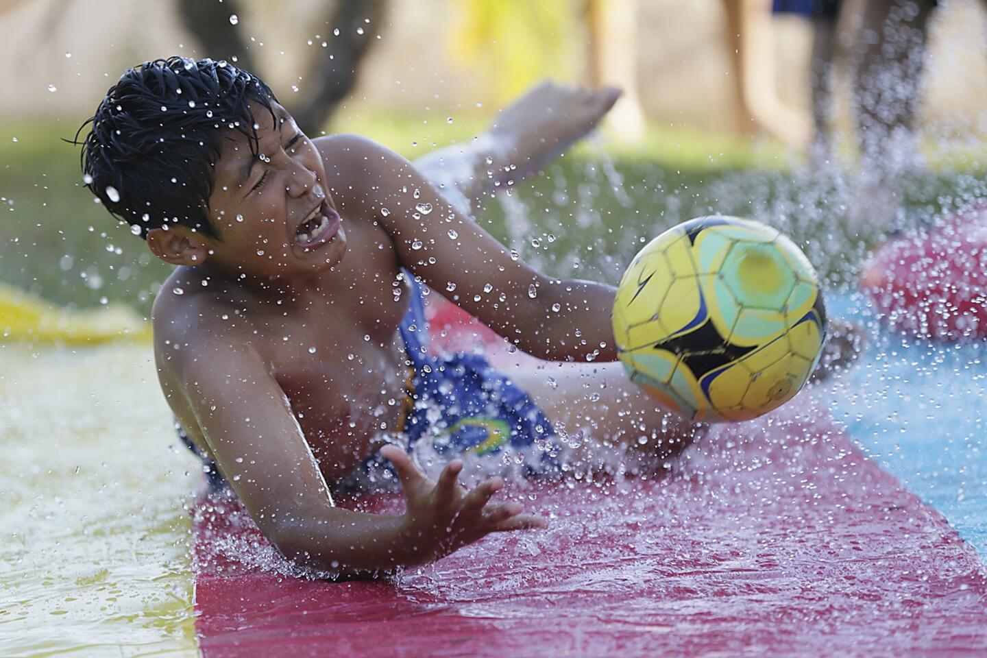 Azusa resident Jose Baltazar, 11, joins friends and relatives in a respite from high temperatures as they frolic on a slip-'n'-slide in Azusa.