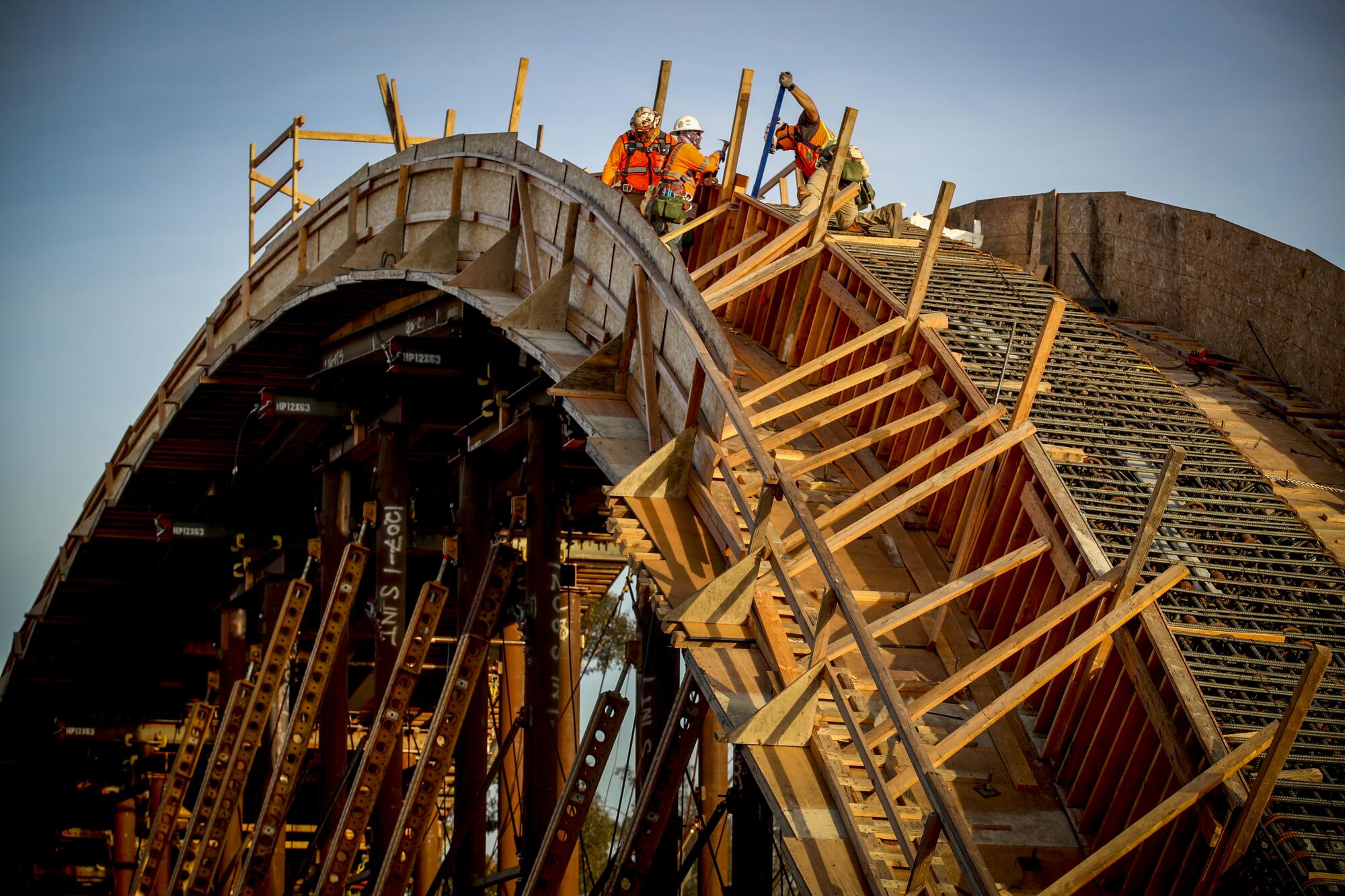 Workers build wooden framework on one arch