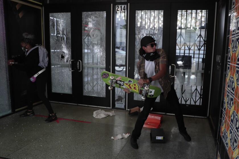 Two people smash windows at the Converse store in Santa Monica.