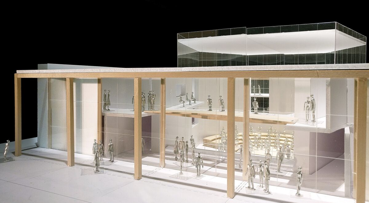 A model shows the exterior of the YOLA Center with a broad glass front and figures visible inside.