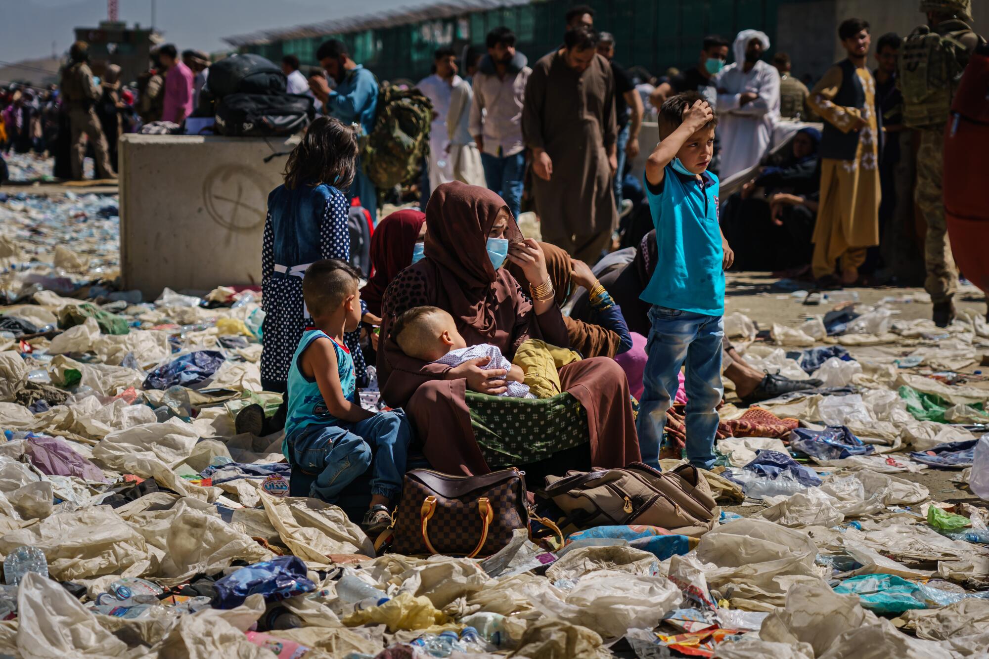 A woman is surrounded by her children as she sits amidst a pile of debris.