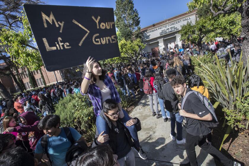 Hamilton High student Sofia Mosqueda, 15, holds a sign while sitting on the shoulders of friend, Christopher Cetrulo,16, during walkout in support of Parkland shooting victims on National Walkout Day in Los Angeles.