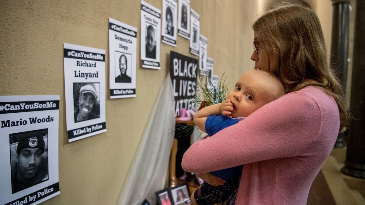 Shawna Reeves holds her son while looking over a memorial to black people who have been killed by police.