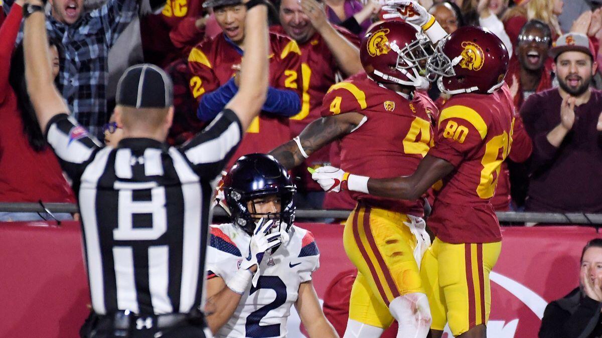 USC wide receiver Steven Mitchell Jr., second from right, celebrates his touchdown with wide receiver Deontay Burnett, right, as Arizona's Lorenzo Burns walks to the sideline during the first half of their Nov. 4 game at the Coliseum.