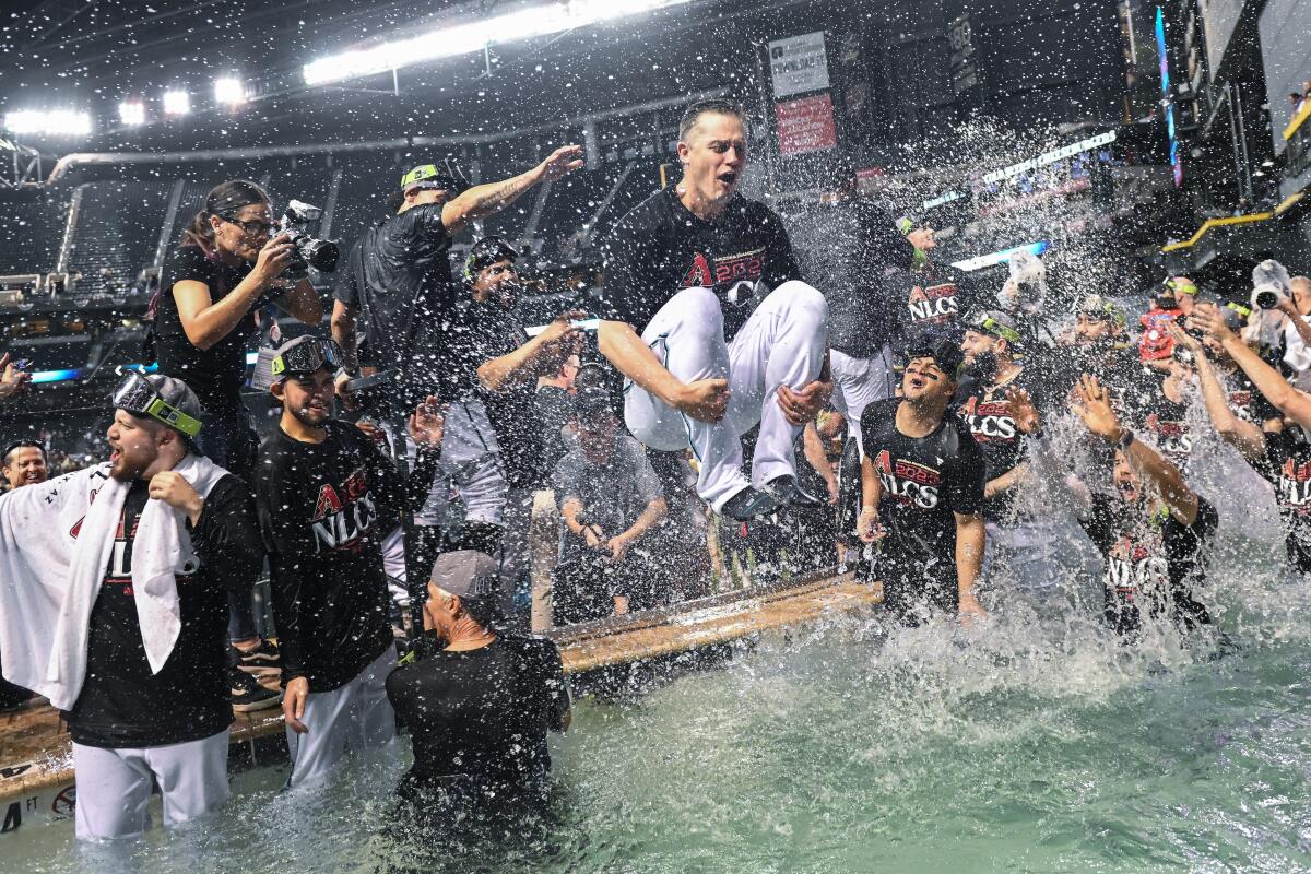 PHOENIX, AZ - October 11: The Arizona Diamondback dive into a pool to celebrate defeating the Los Angeles Dodgers in three games in the National League Division Series at Chase Field on Monday, Oct. 11, 2023, in Phoenix, AZ. (Wally Skalij / Los Angeles Times)