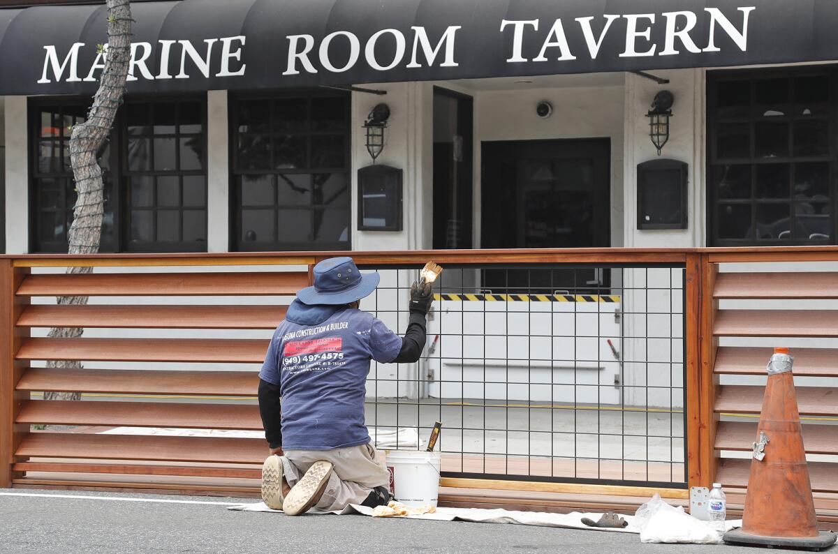 A construction worker adds finish to an outdoor dining deck in front of the Marine Room Tavern on Wednesday, May 19.