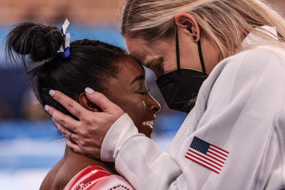 Simone Biles is congratulated by her coach Cecile Landi, who holds Biles' head.