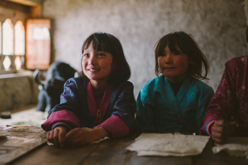Los niños pequeños están sentados en el escritorio de la escuela en "Lunana: Thor Yak en clase."