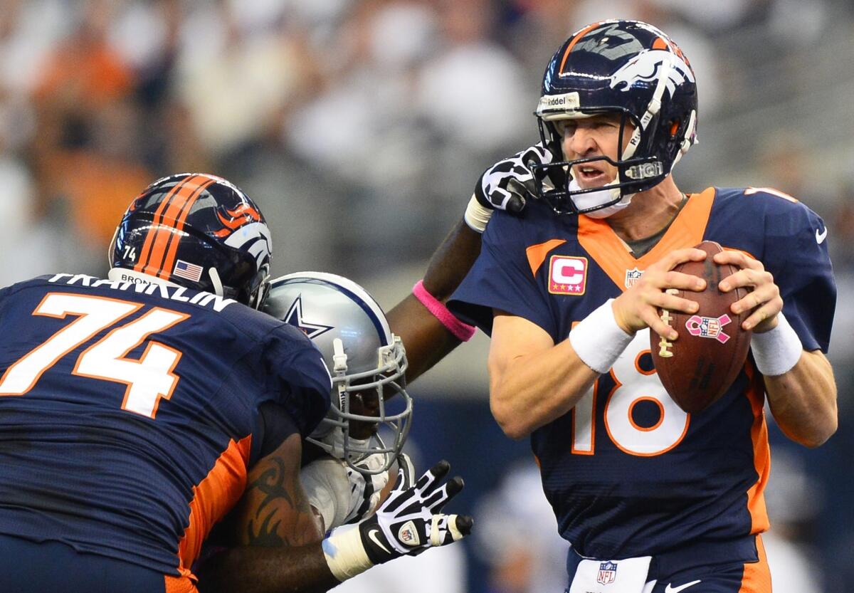 Broncos quarterback Peyton Manning tries to escape the grasp of Cowboys defensive end George Selvie in the first half Sunday.