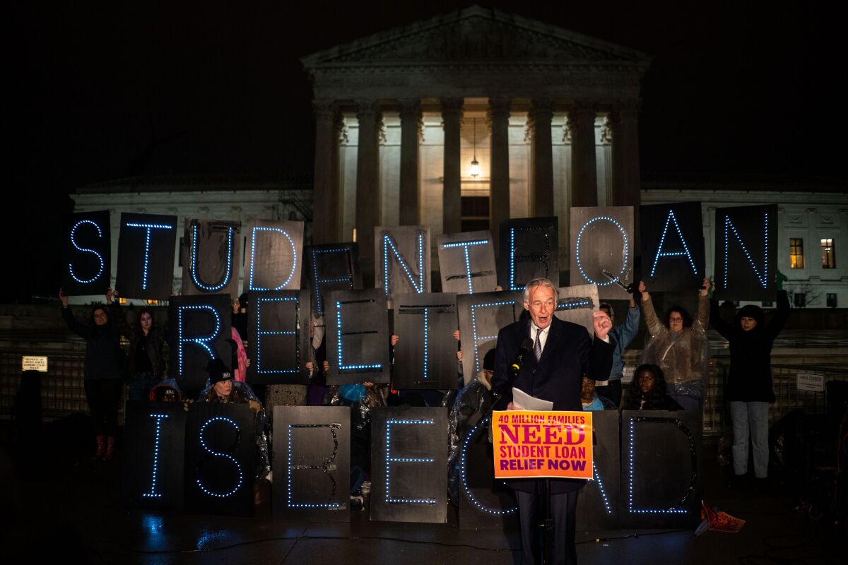 A man in suit and tie addresses an evening rally in front of the Supreme Court