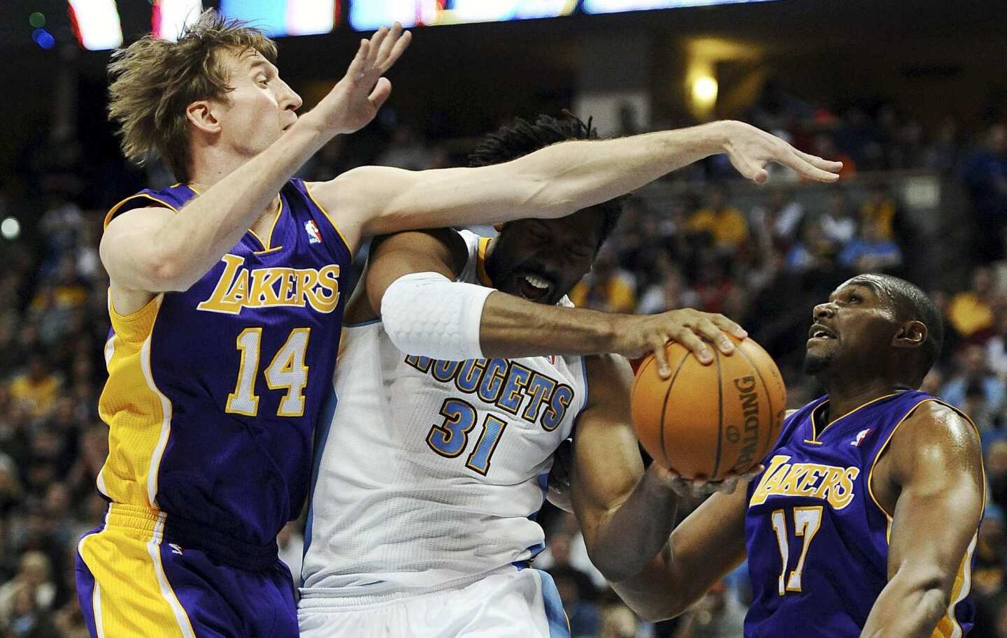 Nuggets center Nene is fouled by Lakers power forward Troy Murphy as they battle for a rebound with Andrew Bynum in the second half Sunday in Denver.