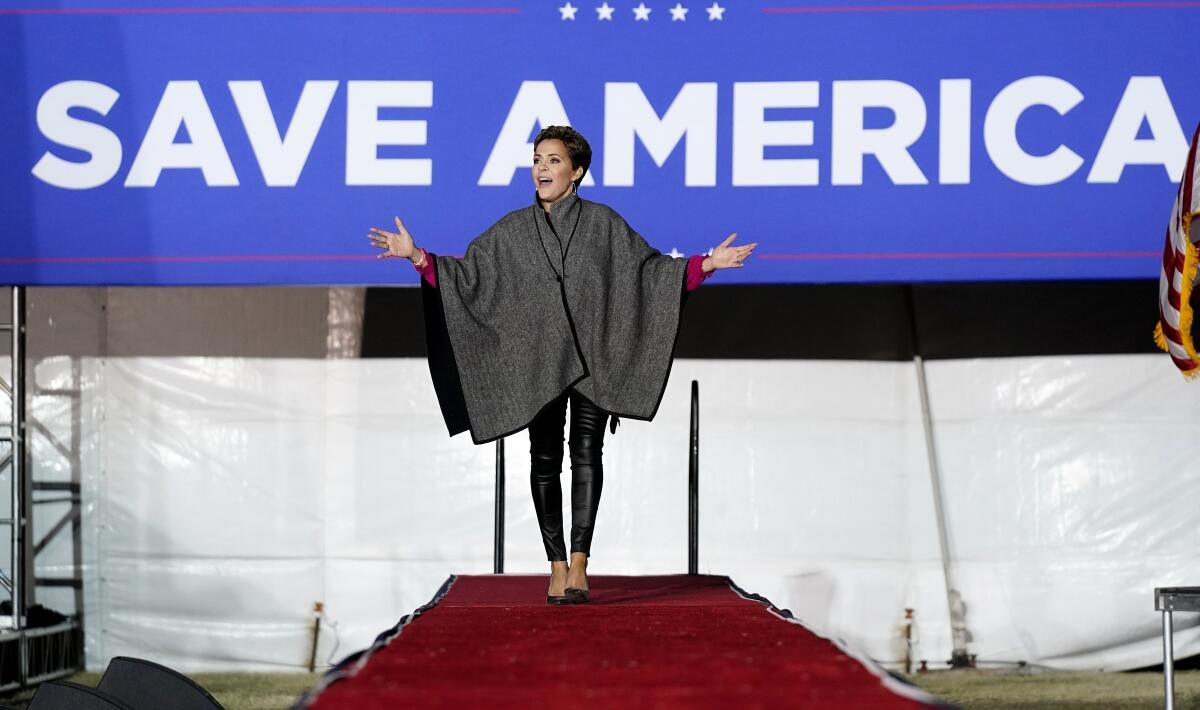 A woman walks down a runway with her arms outstretched. 