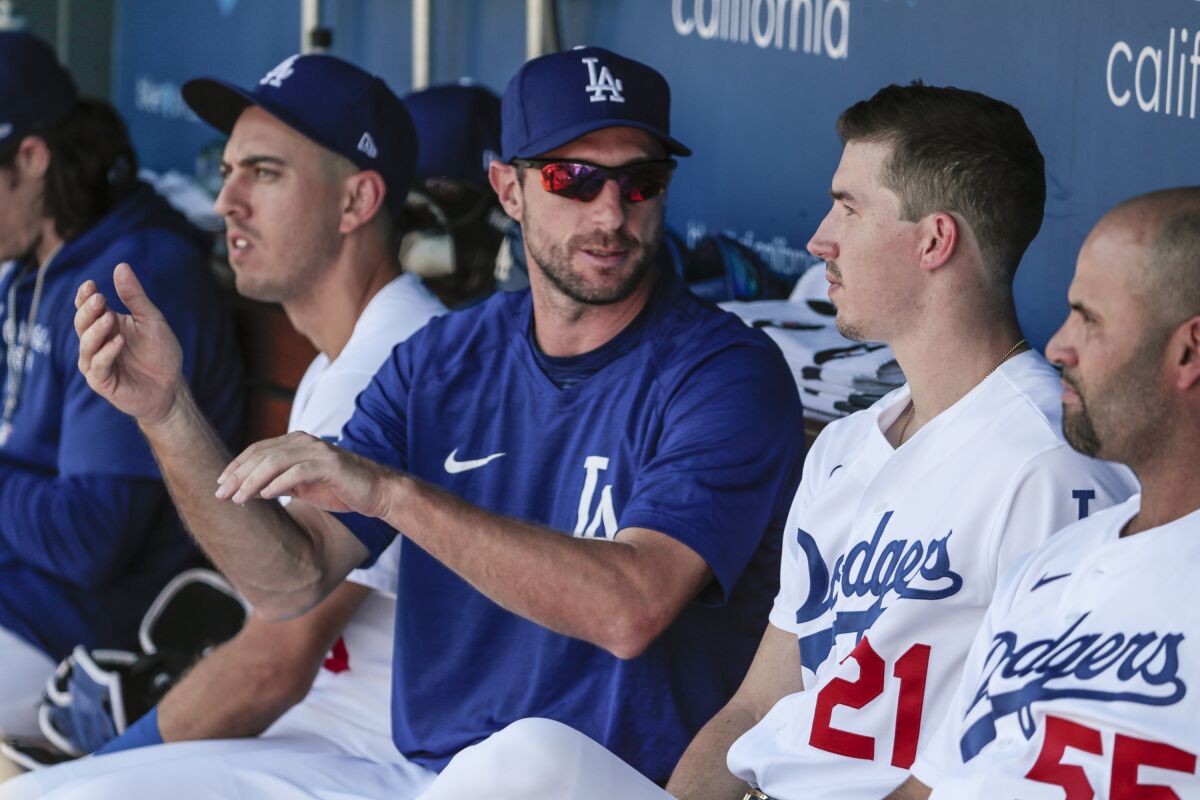 Dodgers starting pitcher Walker Buehler (21) speaks with pitcher Max Scherzer in the dugout.