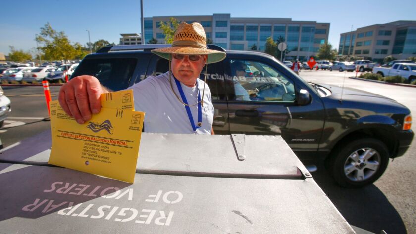 Election worker John Mann deposits mail-in ballots dropped off at the San Diego County Registrar of Voters office into a secured lock box at the drive-thru lane.