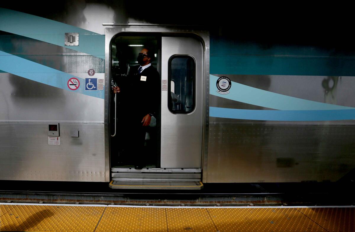 A conductor stands in a doorway as a Metrolink train arrives at Union Station
