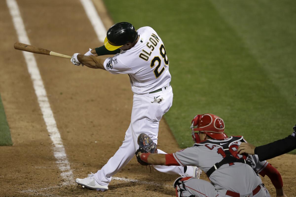 The Athletics' Matt Olson hits a walk-off grand slam in the 10th inning as Angels catcher Jason Castro, right, looks on.