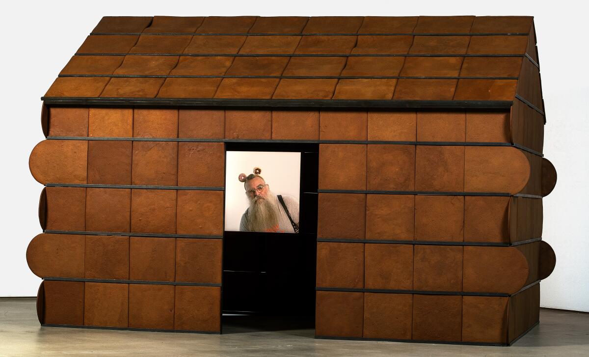 Nayland Blake peers through the window of their gingerbread sculpture "Feeder 2," 1998.