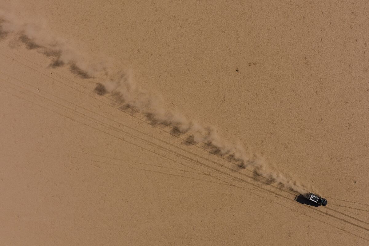 A drone photo of a truck driving across a dry lake bed.