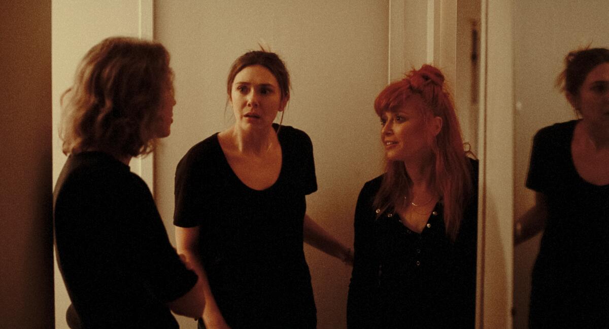 Three women argue in a hallway.
