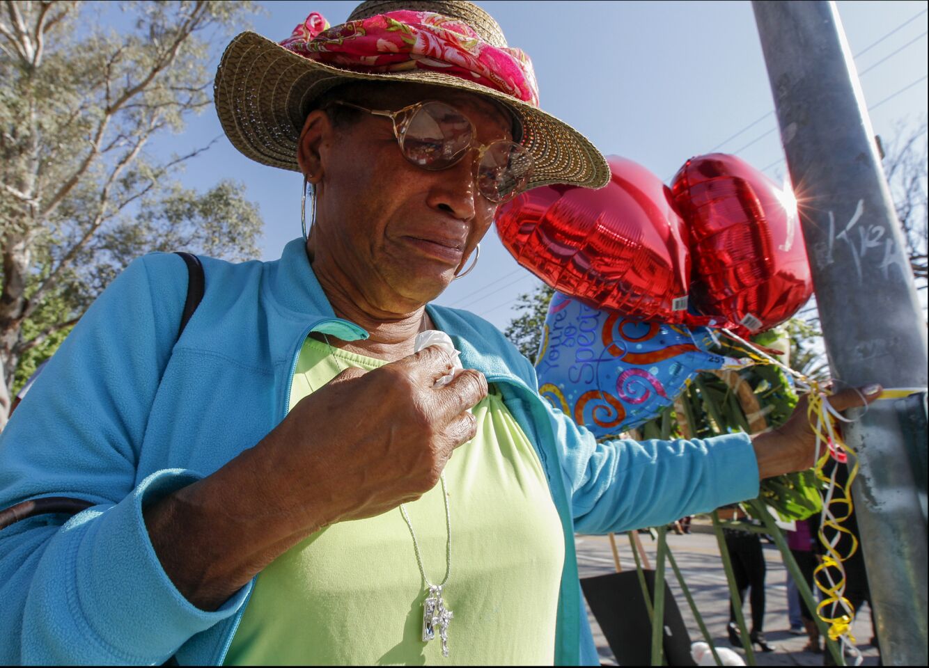 Bobbie Haywood, who lives in the neighborhood, stops by to pay respect at a makeshift memorial for the shooting victims at North Park Elementary School in San Bernardino.