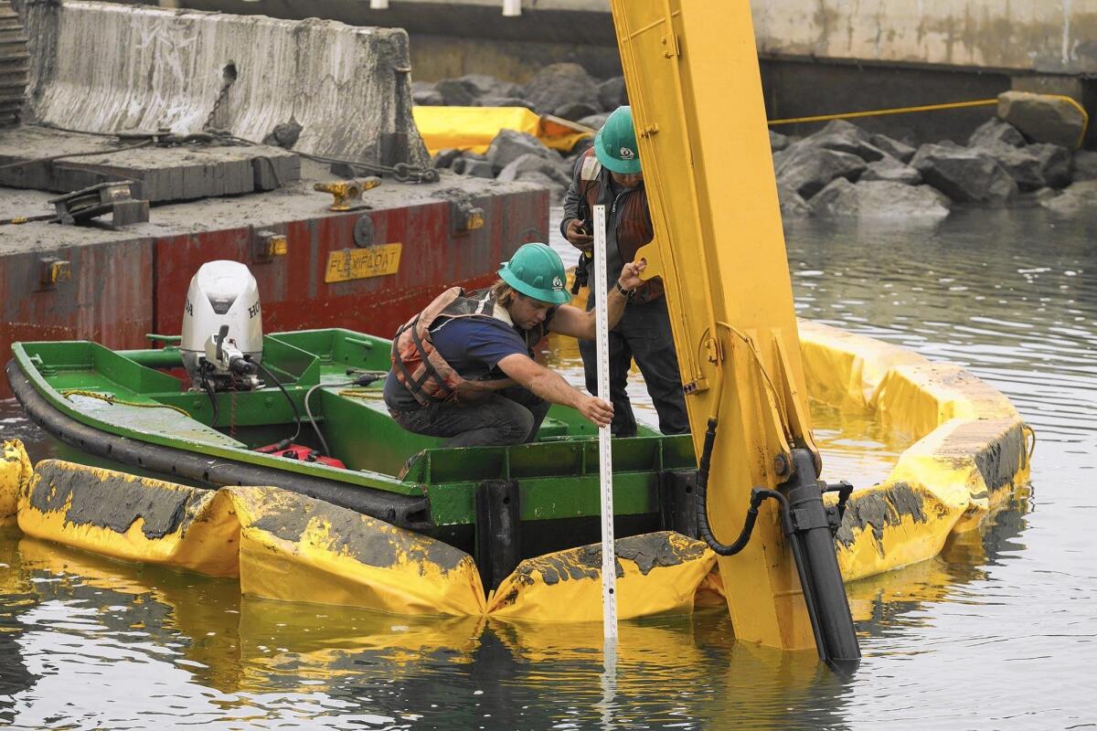 Employees with Associated Pacific Constructors measure the depth while working on the Grand Canal between Balboa Island and Little Balboa Island on Thursday.