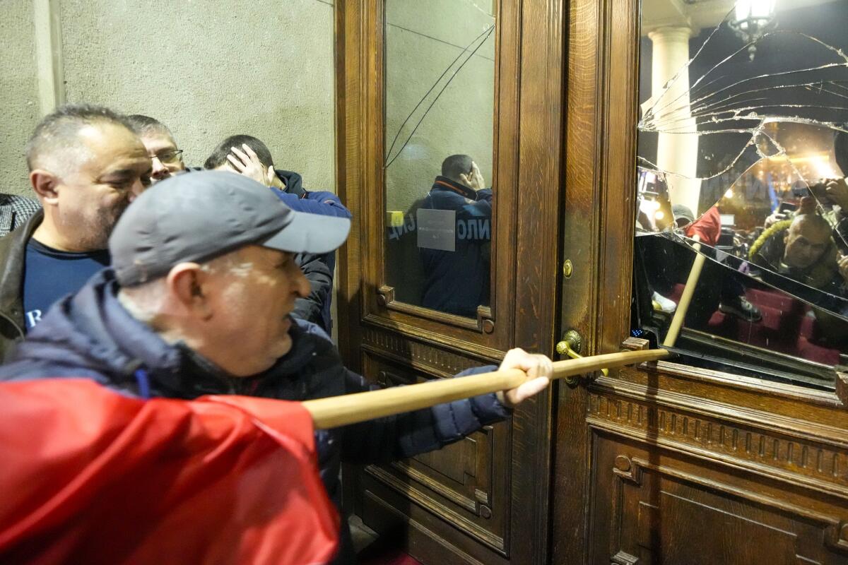 Opposition supporters attempt to enter the capital's city council building by breaking the glass in a door,.