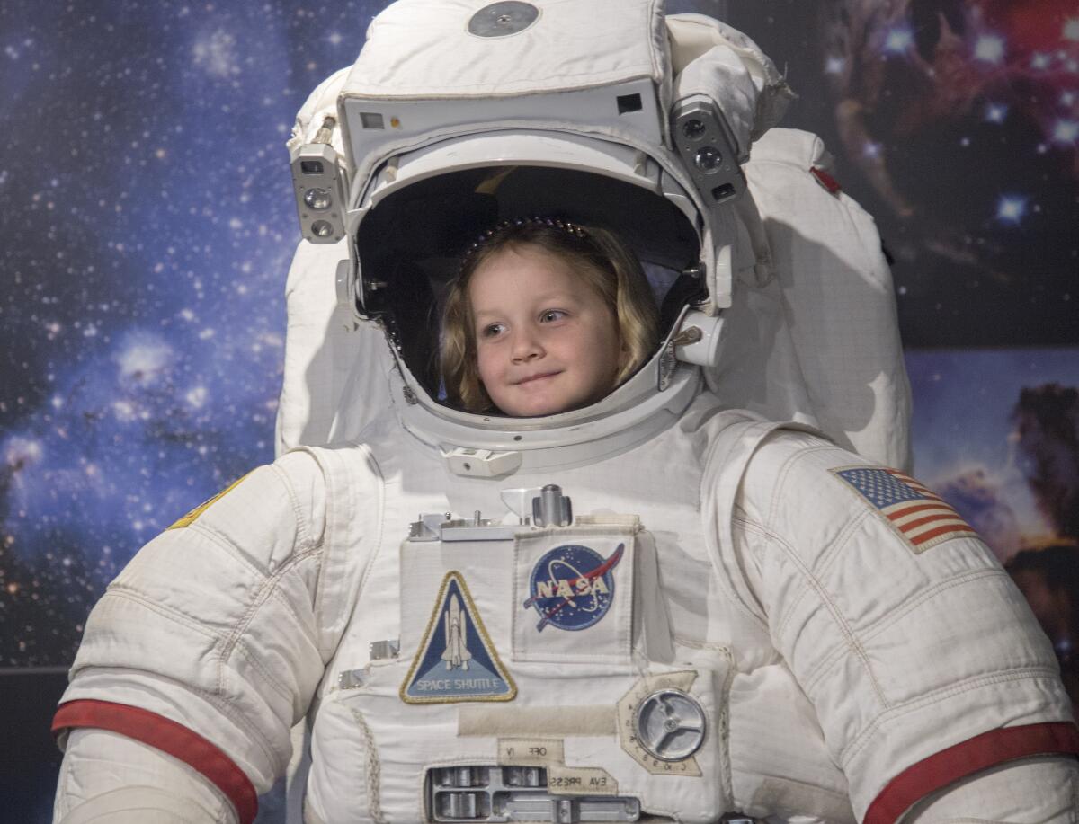 Faith Linenberger, 5, tries on a space suit at the Columbia Memorial Space Center in Downey.