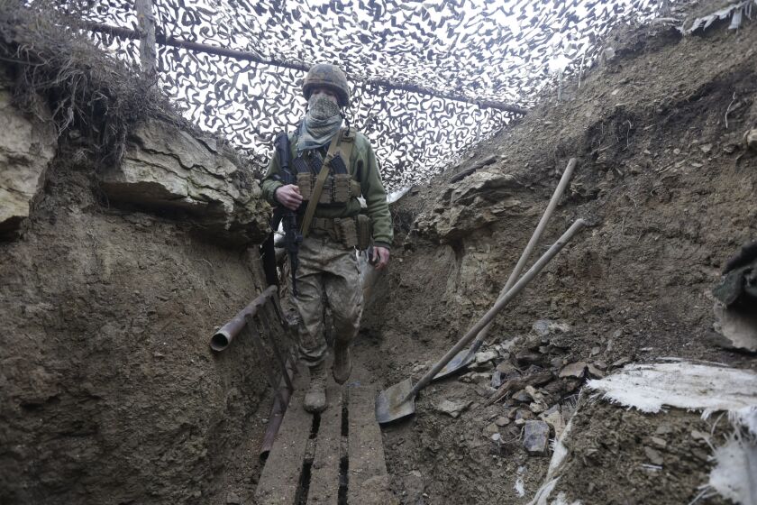 Ukrainian soldiers walks under a camouflage net in a trench on the line of separation from pro-Russian rebels near Debaltsevo, Donetsk region, Ukraine, Ukraine Friday, Dec 3, 2021. In this Friday, the Ukrainian defense minister warned that Russia could invade his country next month. Russia-West tensions escalated recently with Ukraine and its Western backers becoming increasingly concerned that a Russian troop buildup near the Ukrainian border could signal Moscow's intention to invade. (AP Photo/Andriy Dubchak)