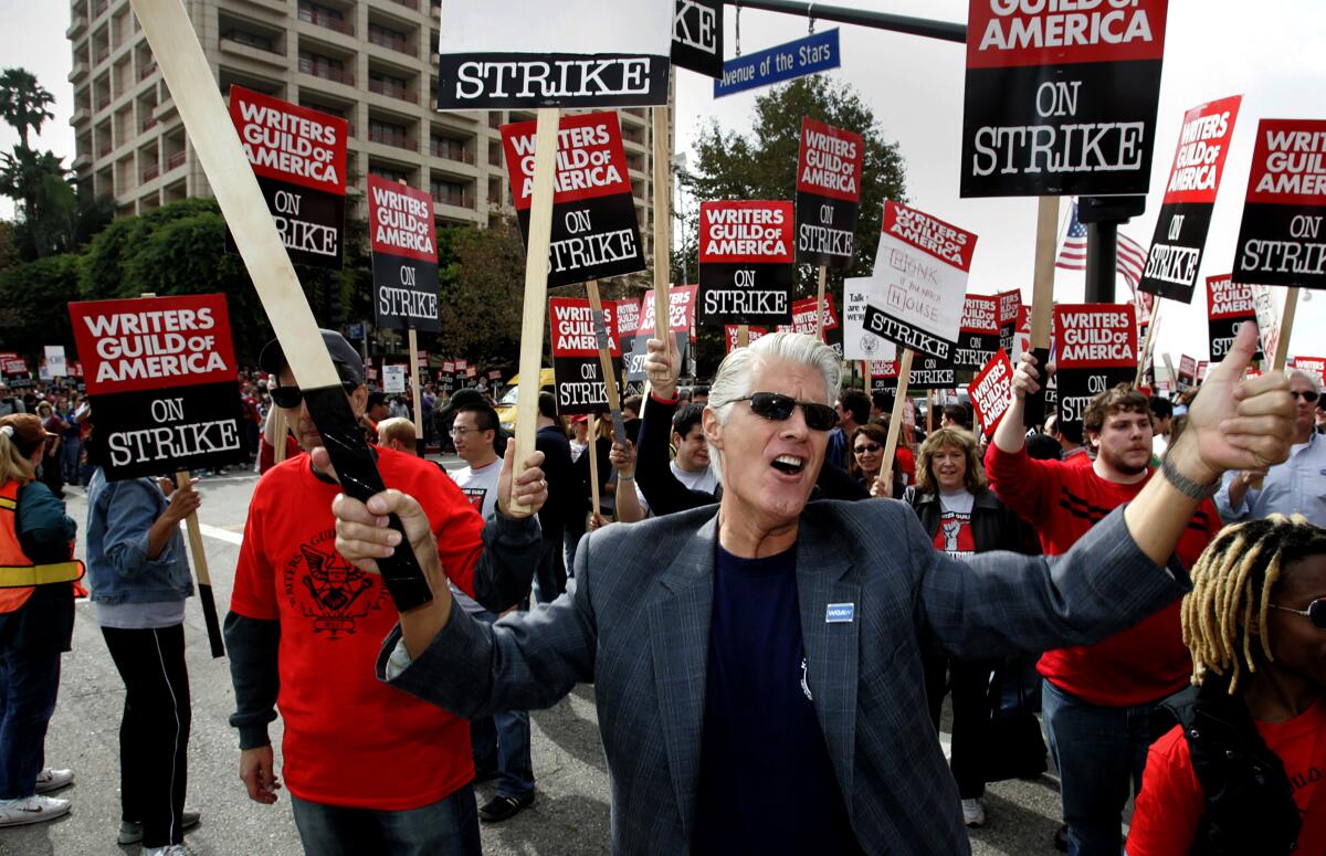 People hold signs that read, "Writers Guild of America on strike."