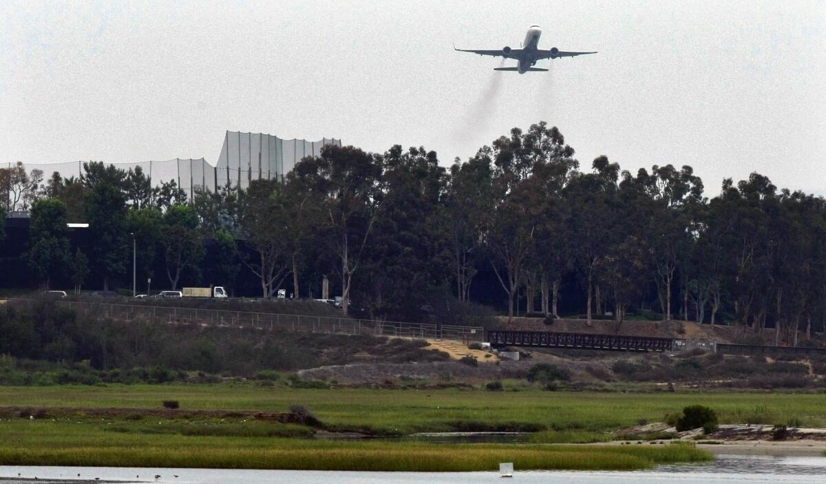 A commercial jet leaves John Wayne International Airport and flies over the Upper Newport Bay. 