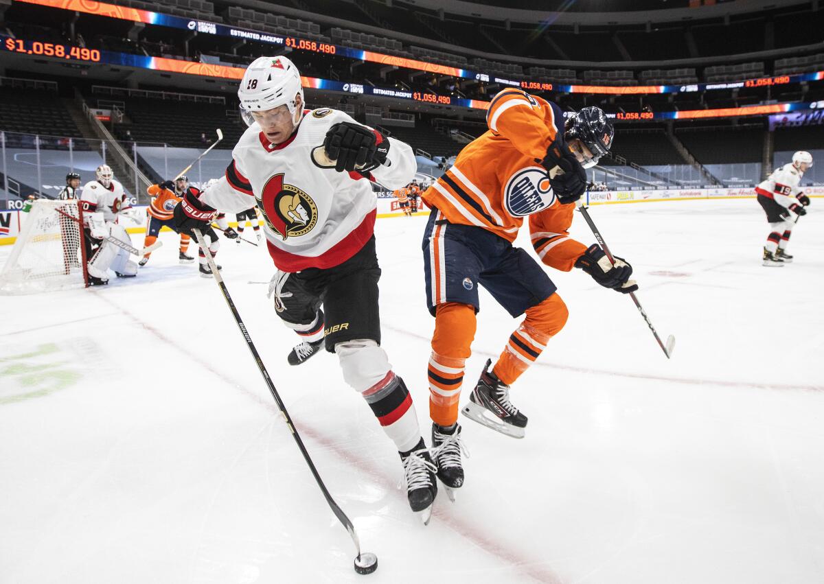Edmonton Oilers' Jujhar Khaira (16) and Ottawa Senators' Tim Stuetzle (18) battle for the puck during the second period of an NHL hockey game, Wednesday, March 10, 2021 in Edmonton, Alberta. (Jason Franson/The Canadian Press via AP)