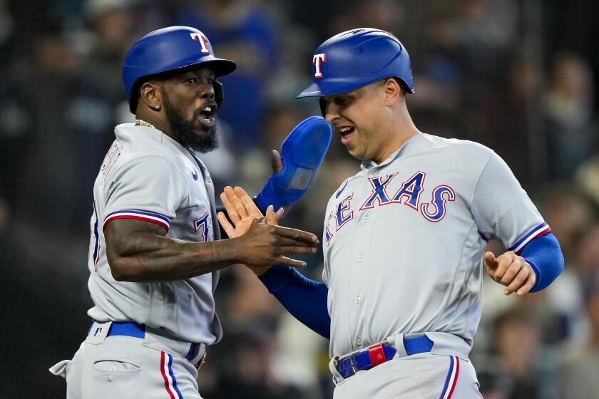Texas Rangers' Adolis García, left, greets Nathaniel Lowe as they score on a two-run double from Jonah Heim against the Seattle Mariners during the third inning of a baseball game, Saturday, Sept. 30, 2023, in Seattle. (AP Photo/Lindsey Wasson)