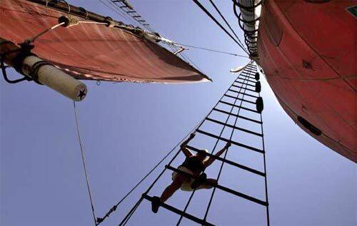 A crew member on the American Pride climbs up for a look at the sails.