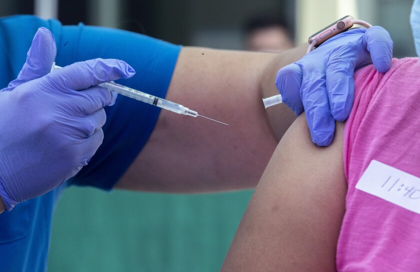 A closeup of a health worker giving someone a vaccination.