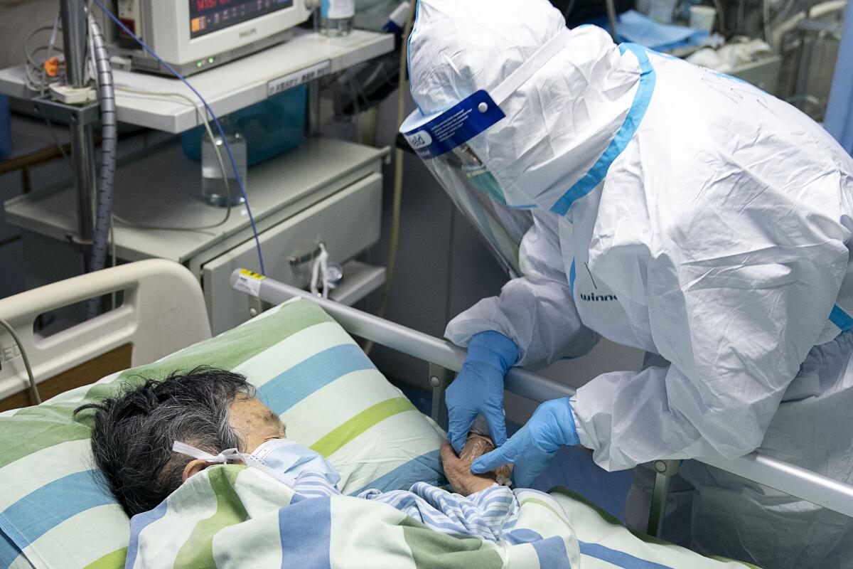 In this photo released by China's Xinhua News Agency, a medical worker attends to a patient in Wuhan. Below, medical student Matthew Crane writes that when he gave a presentation about coronavirus in January, it didn't even have a name.