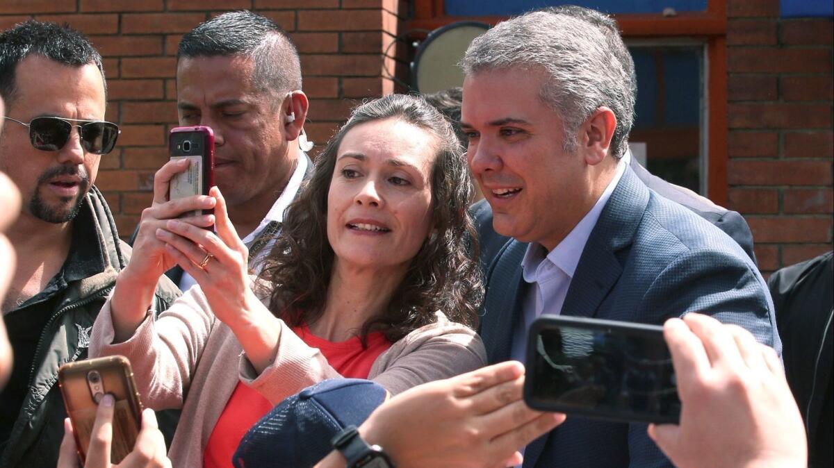 Presidential candidate and eventual winner Ivan Duque, right, poses for a selfie with a supporter as he arrives at his polling station for the second round of presidential elections on Sunday in Bogota, Colombia.