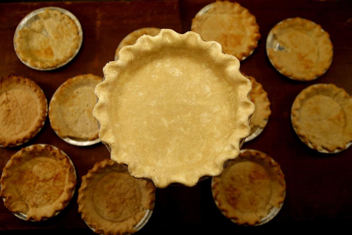 An empty pie crust surrounded by empty tart crusts