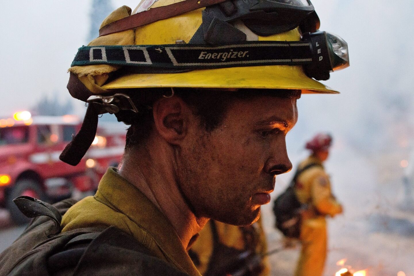 A weary firefighter stares into the flames during a 24-hour shift near Pollock Pines, Calif.